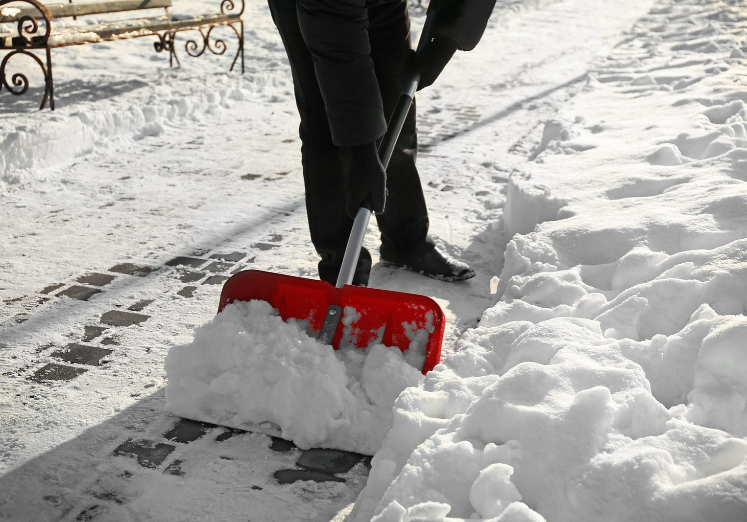 Man removing snow with red shovel WALKWAY SHOVELING